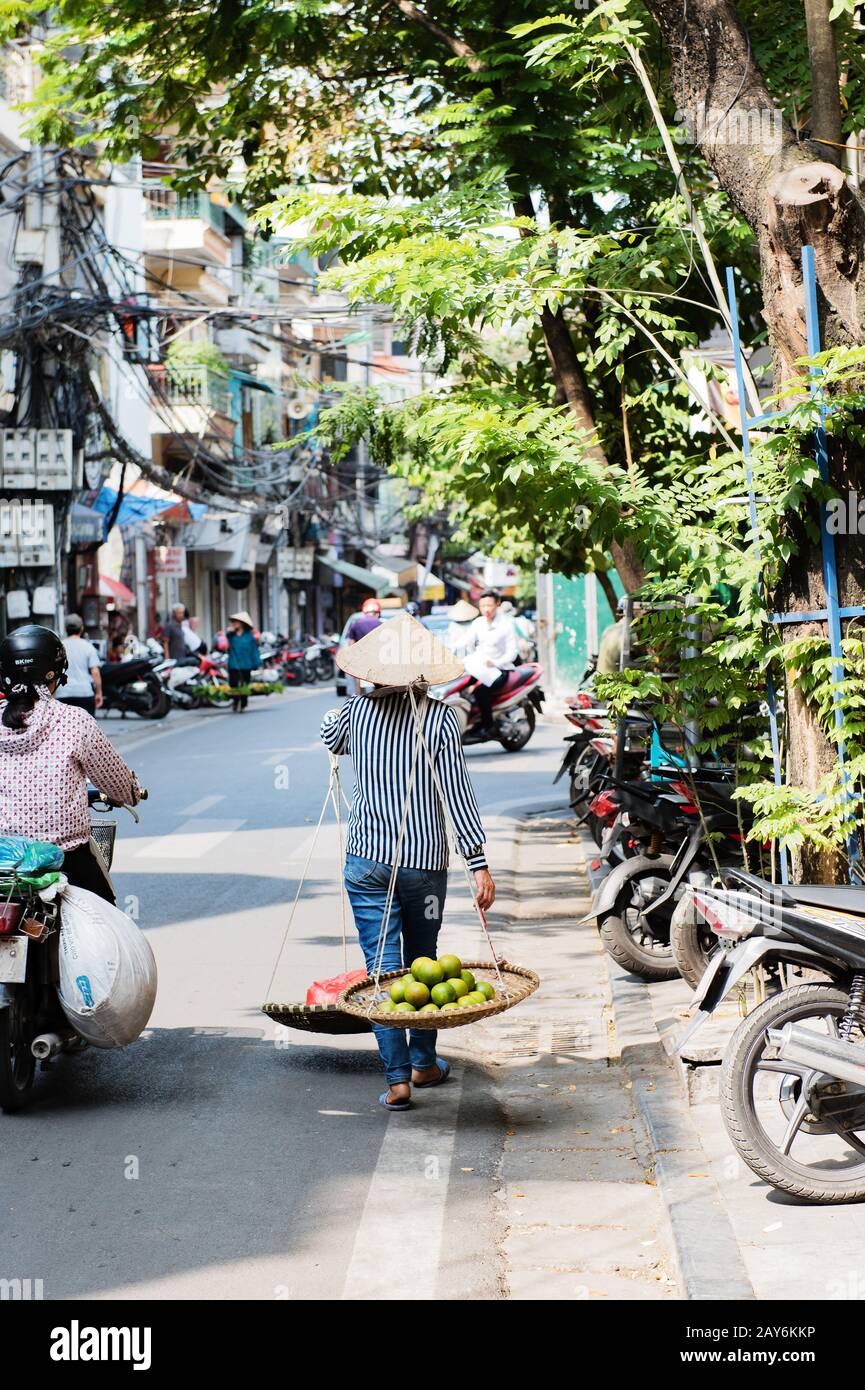 Vietnamese woman carrying baskets of fruit and vegetables on the street in Hue, Vietnam Stock Photo