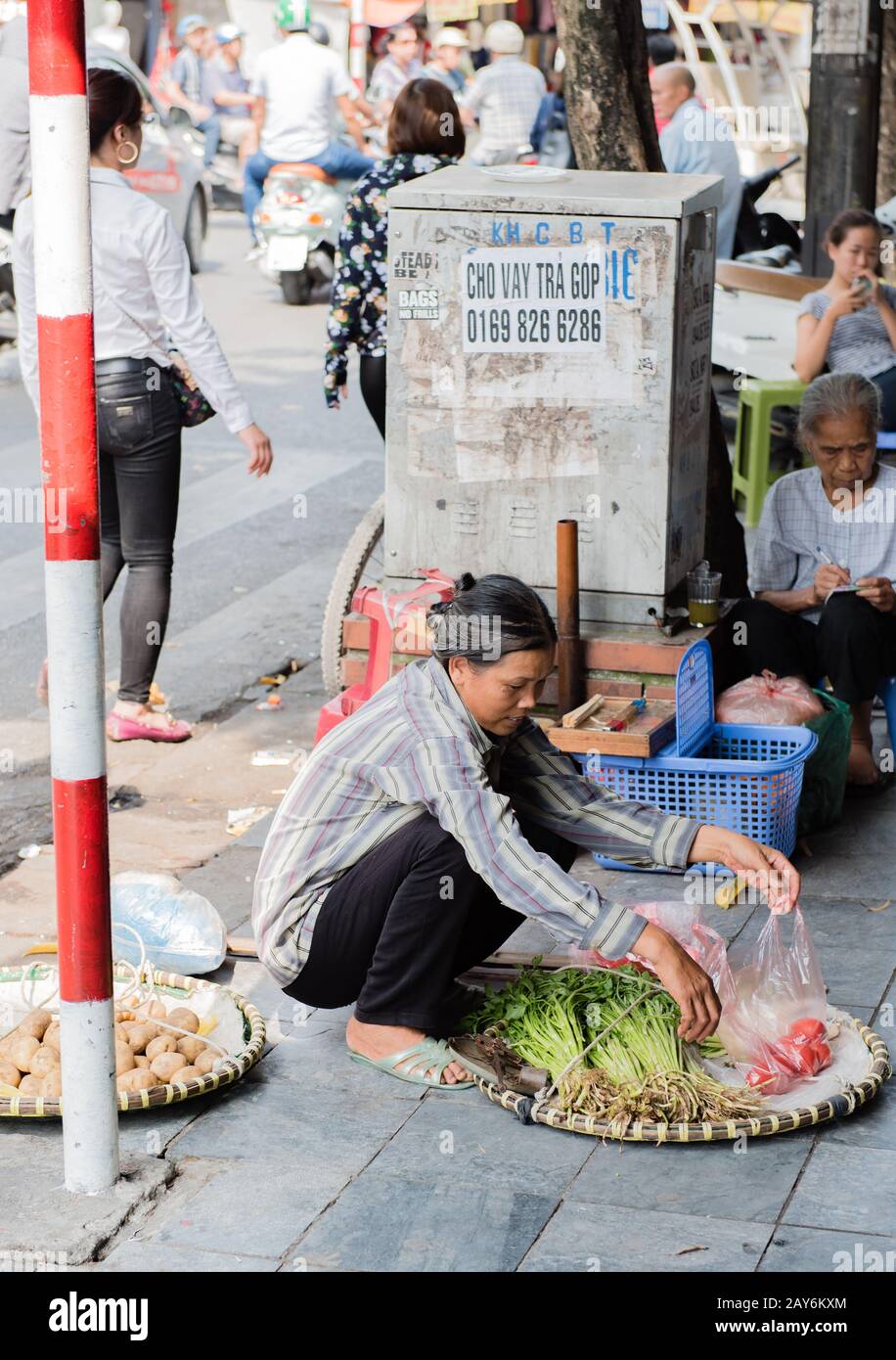 Vietnamese street vendors act and sell their vegetables and fruit products in Hanoi, Vietnam Stock Photo