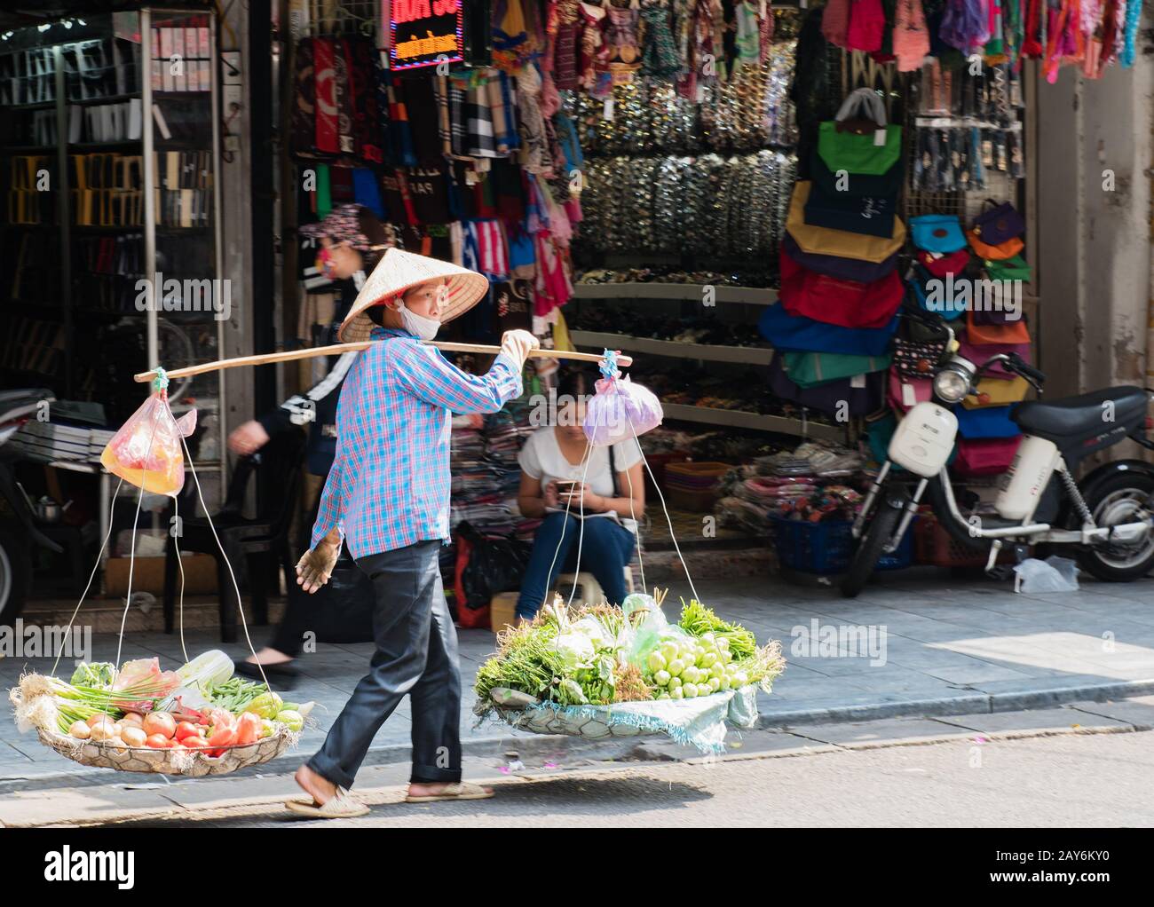 Vietnamese woman carrying baskets of fruit and vegetables on the street in Hue, Vietnam Stock Photo