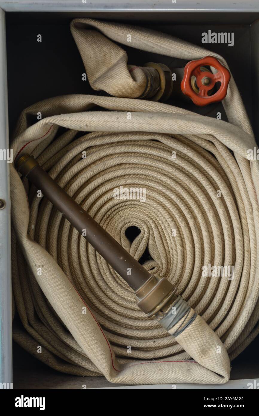 historical coiled fire hose with spray nozzle - close-up Stock Photo