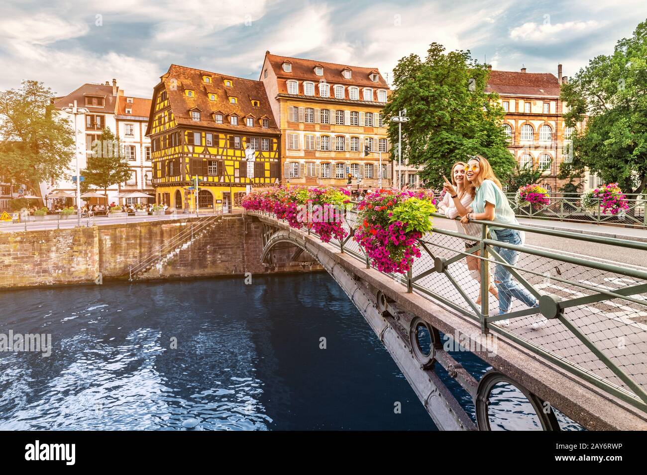 Two young happy girl friends standing on a bridge in Strasbourg while travelling in Petit France region. Tourism and friendship concept Stock Photo