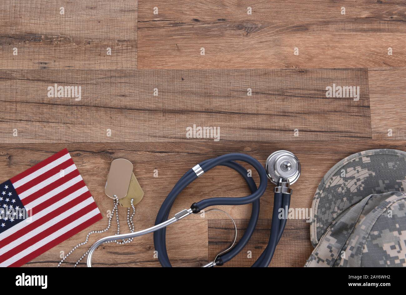 Military Health Care Concept. Camo hat, dog tags, stethoscope, pills, and American Flags on a wood background. Stock Photo