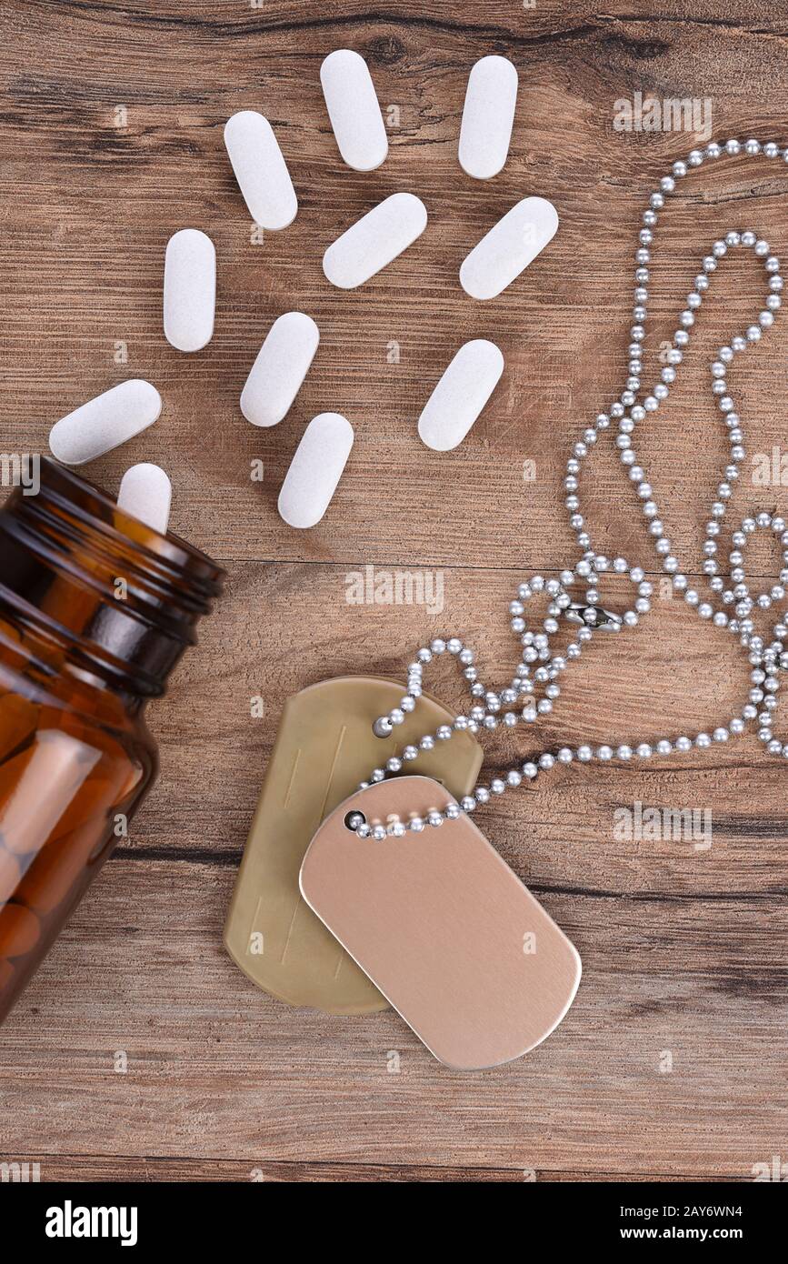 Military and Veterans Health Care Concept. Dog tags and pills on a wood background. Stock Photo