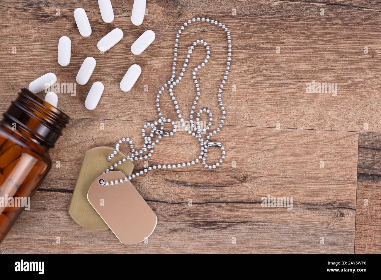 Military and Veterans Health Care Concept. Dog tags and pills on a wood background with copy space. Stock Photo