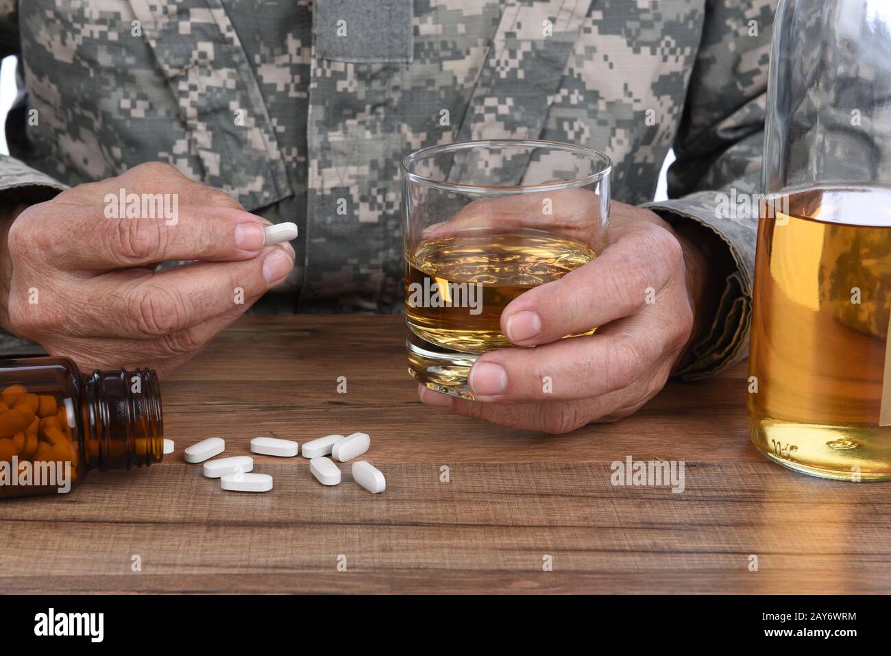 Military Drug and alcohol abuse concept. Closeup of soldier with whiskey and pills to treat his PTSD symptoms. Stock Photo