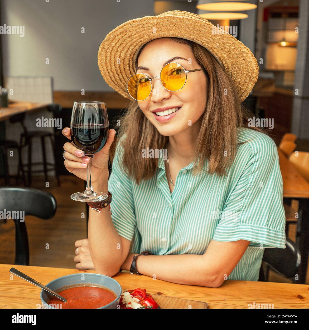 Happy Asian girl eating in restaurant and drinking red wine. Italian or