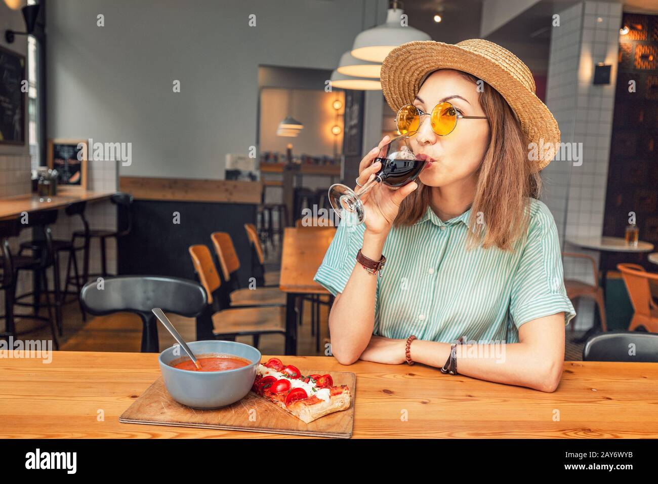 Happy Asian girl eating in restaurant and drinking red wine. Italian or