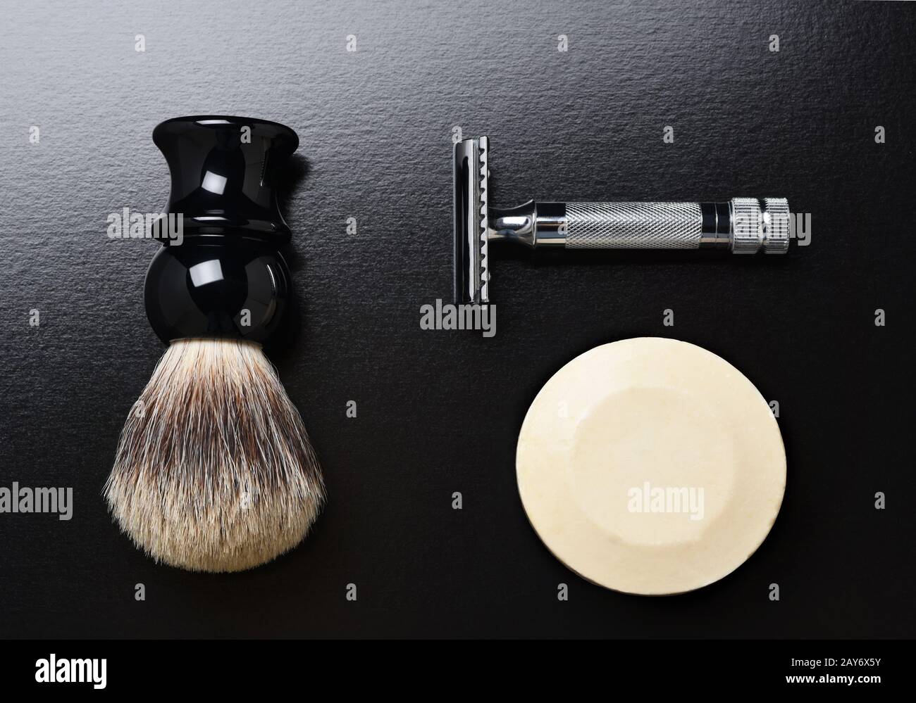 Flat Lay Shaving Still Life. A razor shaving brush and bar of soap on black. Stock Photo