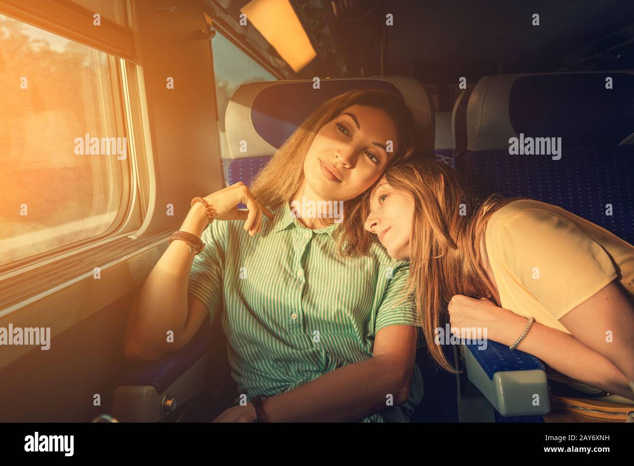 Two women Friends looking at sunset while traveling by train. Candid authentic moment Stock Photo