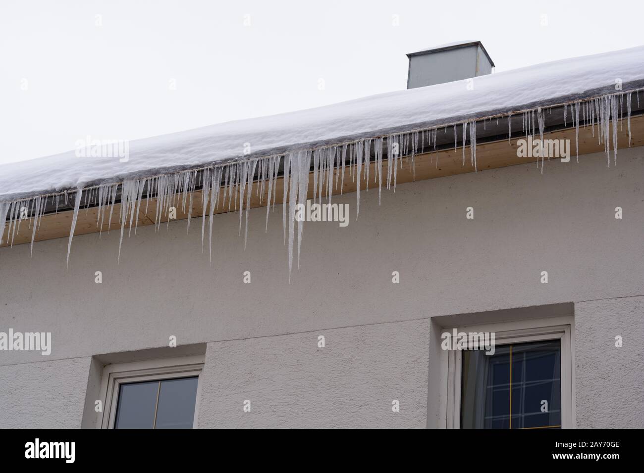 Icicles and snow hang idyllically from the roof of a house Stock Photo
