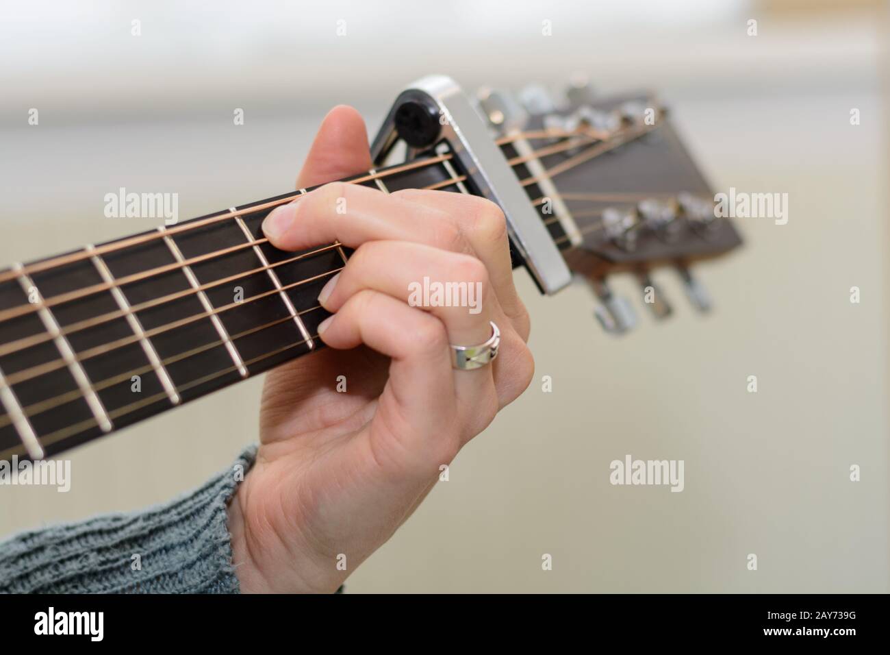 Person plays guitar with capo and gripping hand - detail view Stock Photo