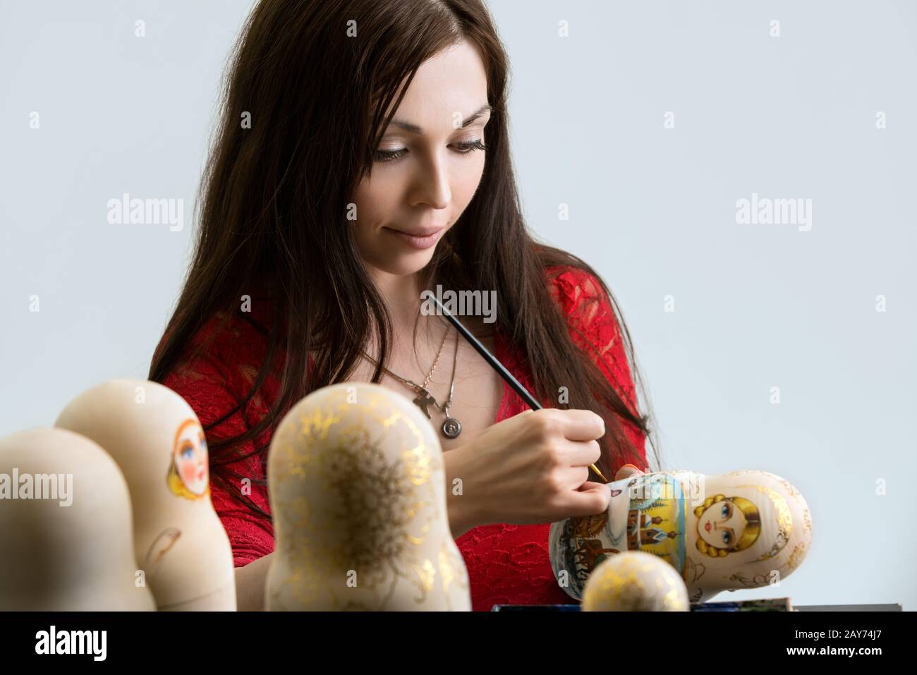 Pretty woman drawing patterns on matrioshka Stock Photo