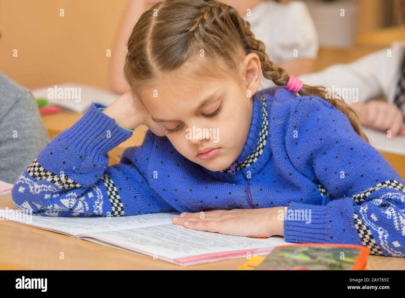 First grader at reading lesson reading text sitting at a school desk Stock Photo