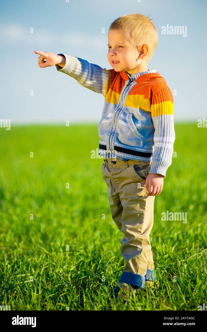 Portrait of happy joyful beautiful little boy outdoor at countryside. Pointing concept. Stock Photo