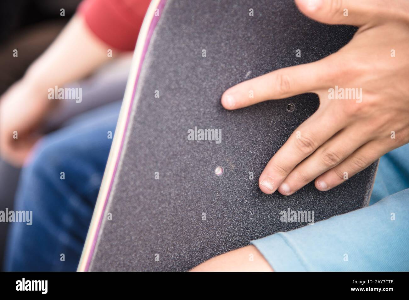 Boy makes bolt holes on the griptape on a skateboard Stock Photo
