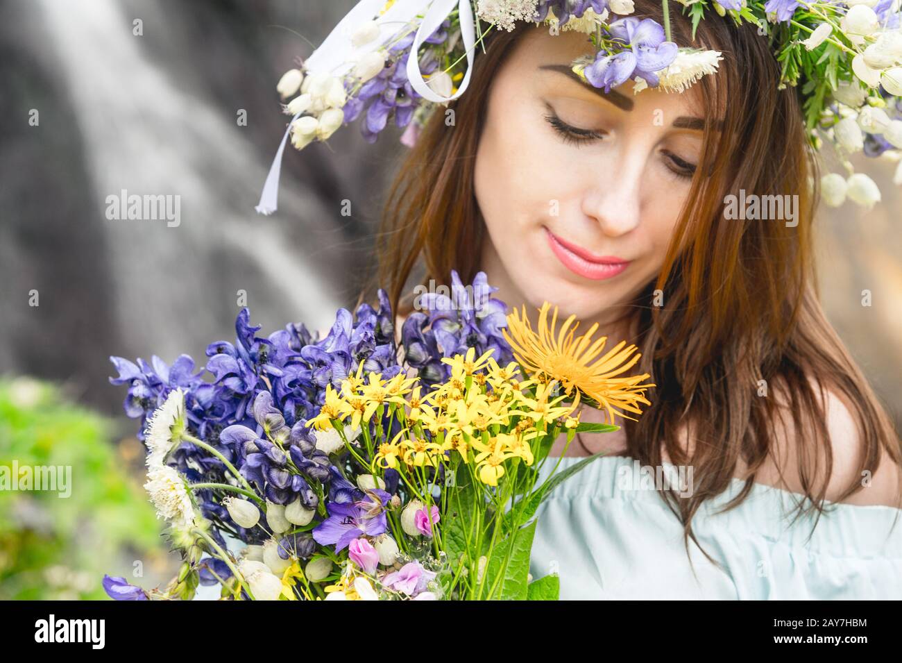 Portrait of a girl with a wreath on her head and a bouquet of flowers ...
