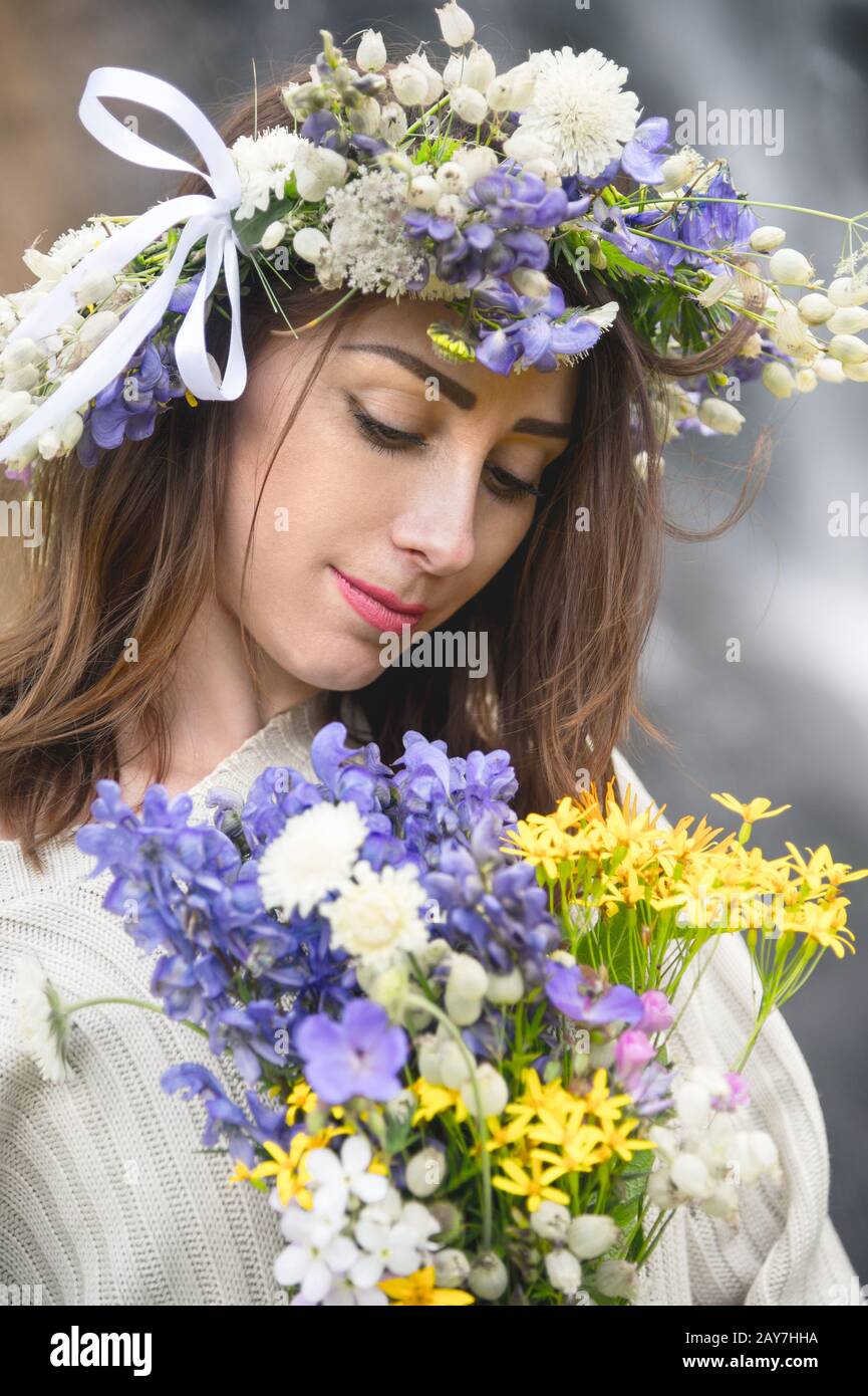 Portrait of a girl with a wreath on her head and a bouquet of flowers ...