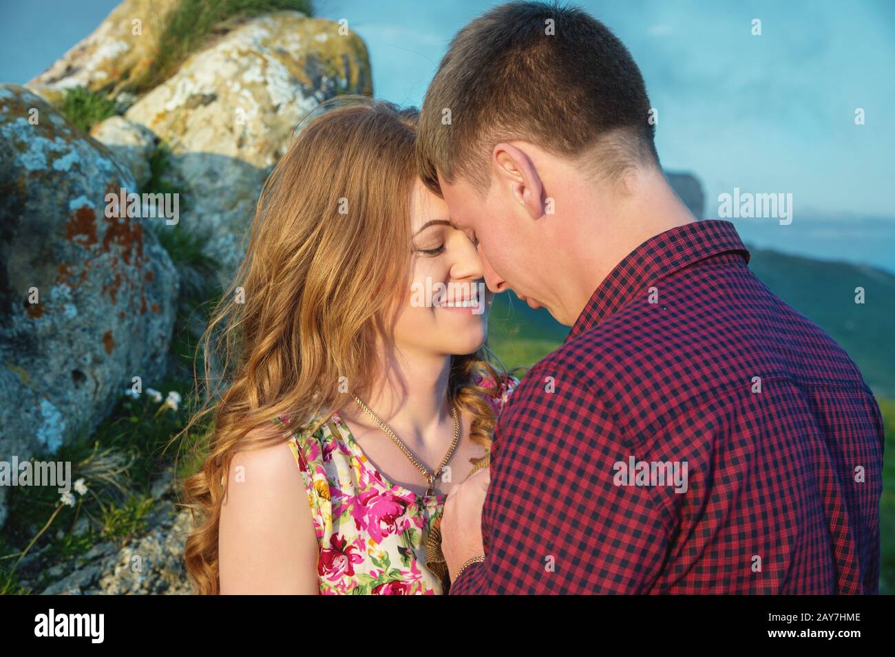 Young happy couple kissing on nature against the beautiful Caucasian ...