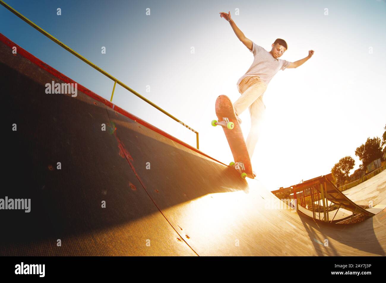 Teen skater hang up over a ramp on a skateboard in a skate park Stock Photo