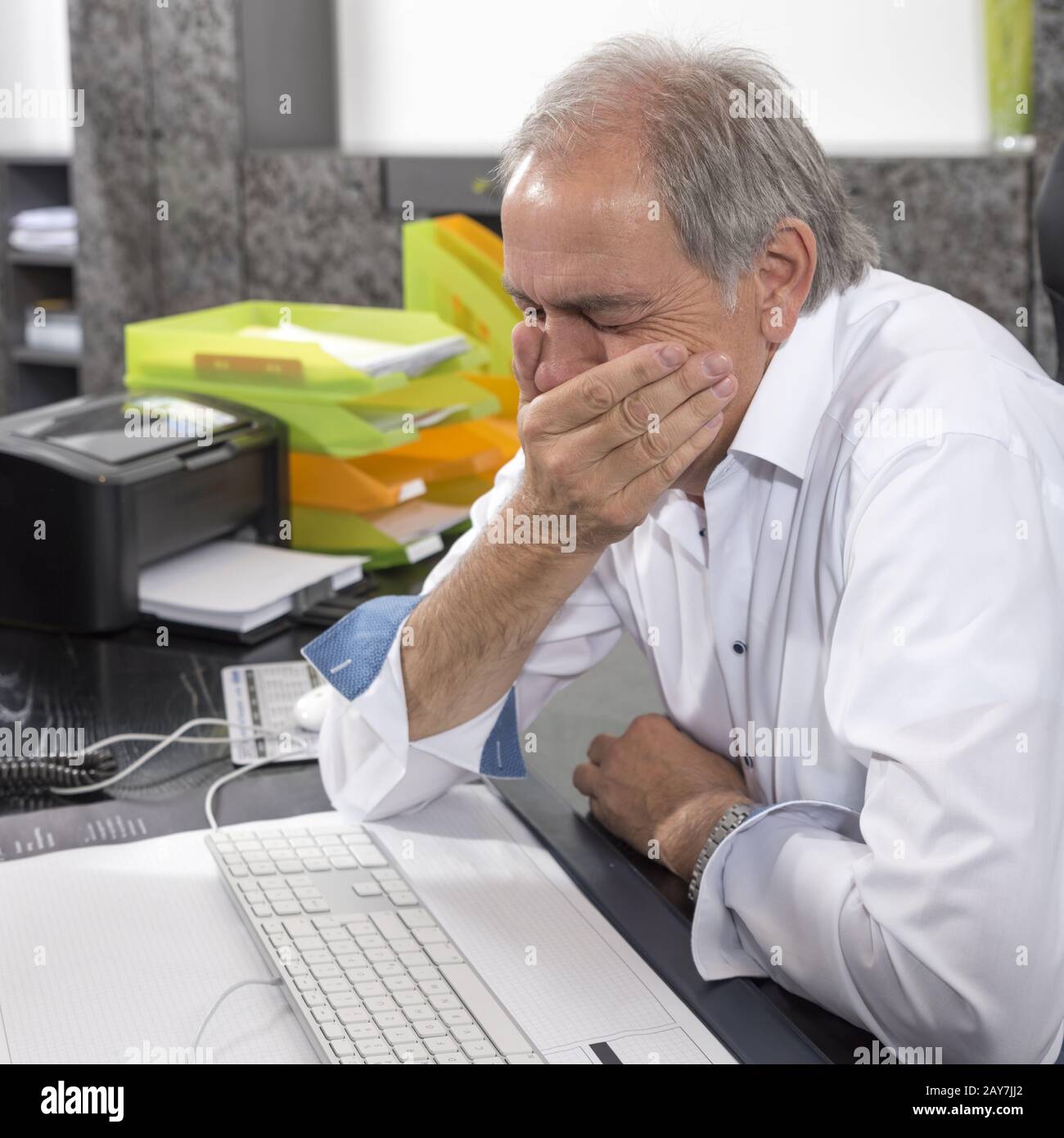 Senior man sitting desperately at a desk Stock Photo