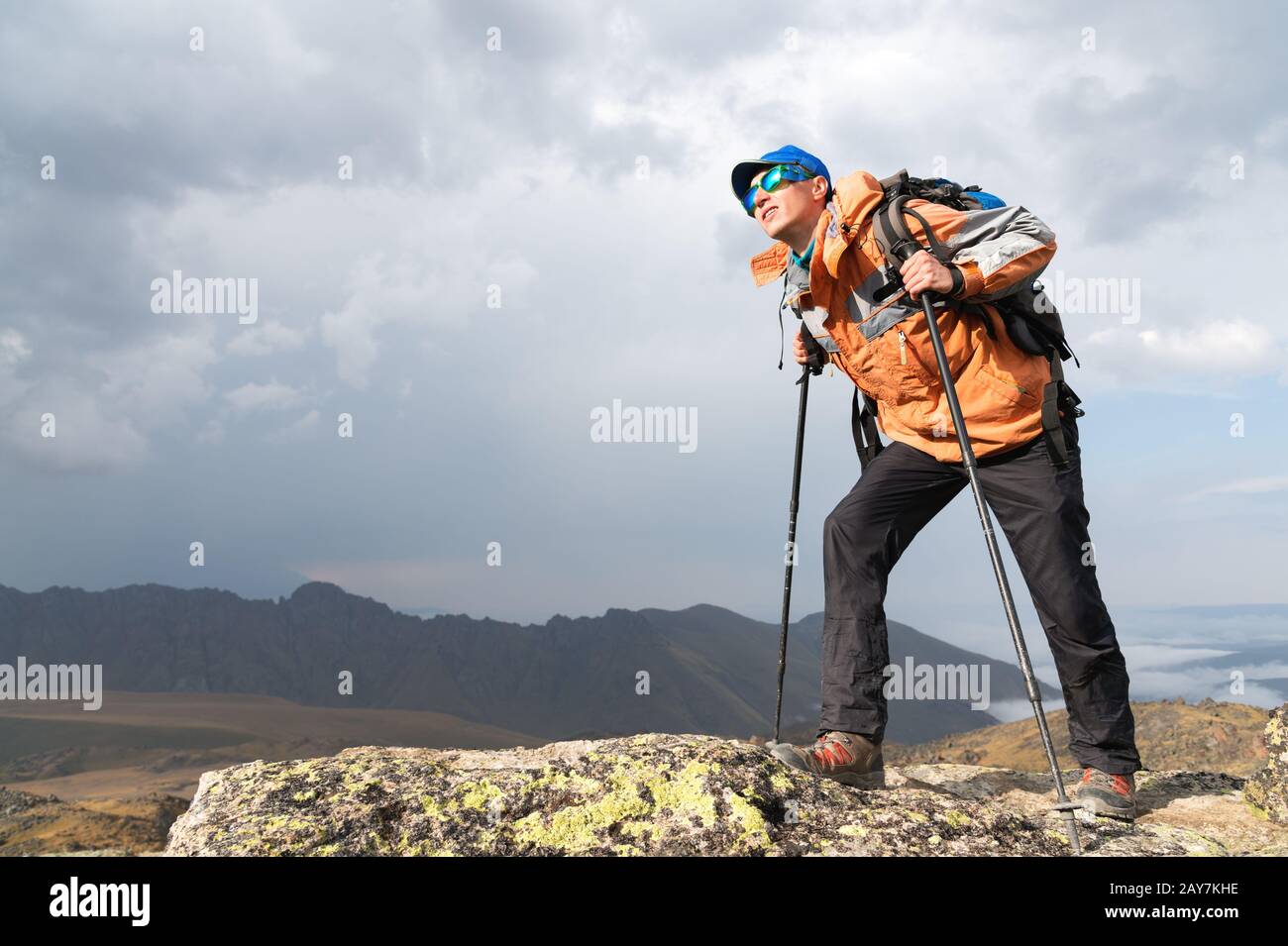 A lonely tourist enjoys the views high in the mountains where there is no grass of the village and snow Stock Photo