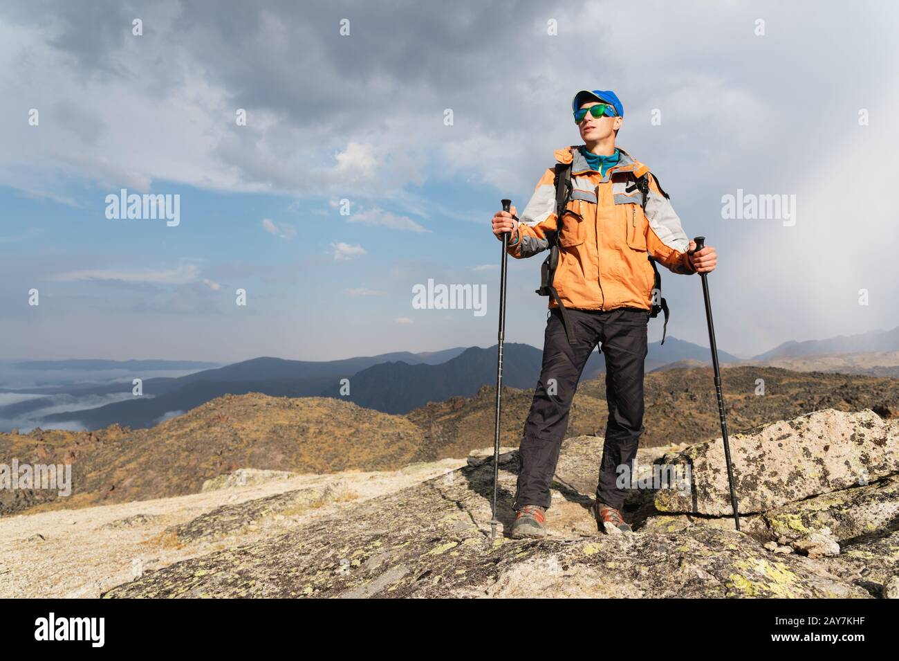 A lonely tourist enjoys the views high in the mountains where there is no grass of the village and snow Stock Photo