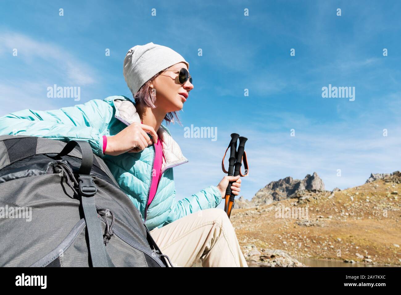 A Tourist Girl Wearing Sunglasses Down Jacket And Hat With A Backpack And Mountain Equipment With Handles For Tracking In Her Ha Stock Photo Alamy