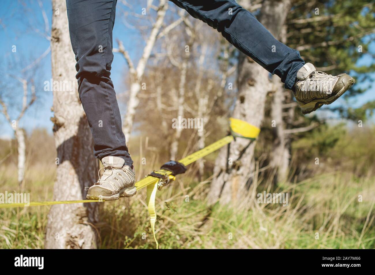 Slacklining is a practice of balancing, in which nylon or polyester fabric stretched between two anchor points is commonly used. Stock Photo
