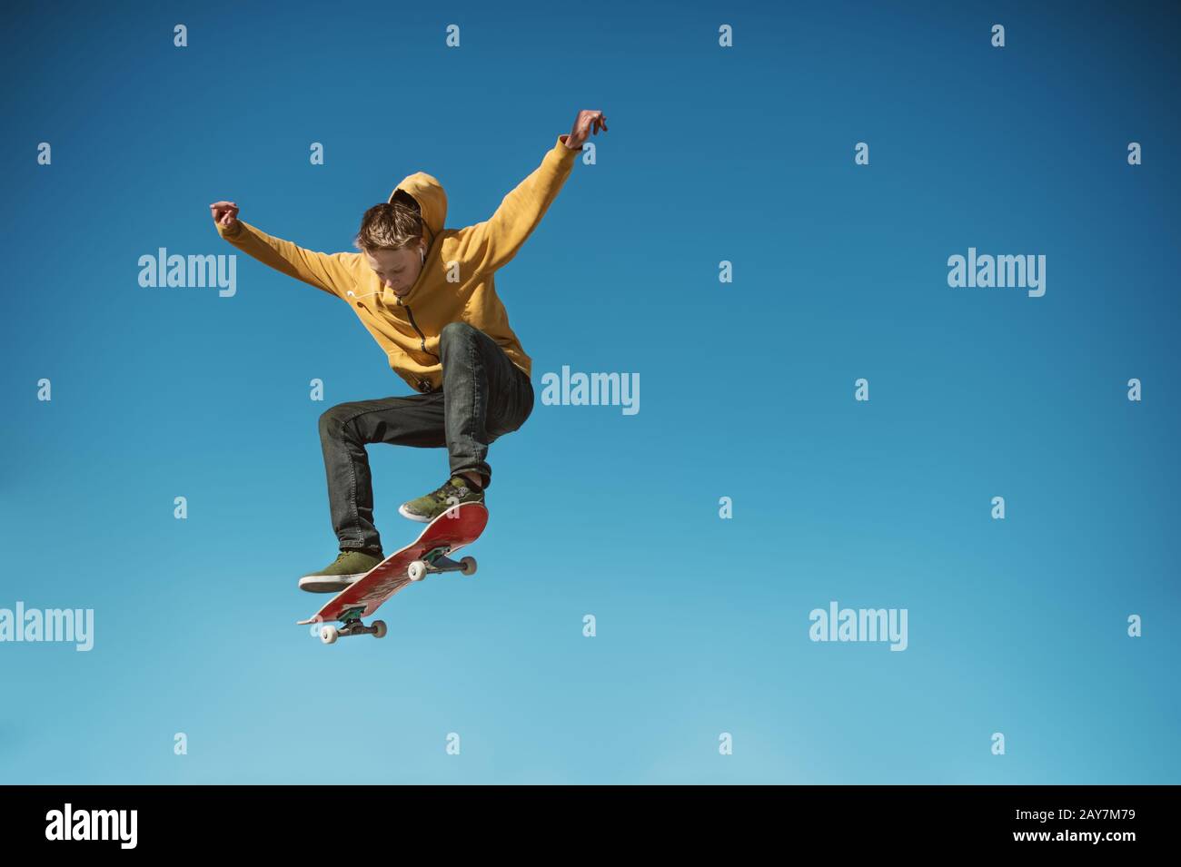 A teenager skateboarder does an ollie trick on background of blue sky gradient Stock Photo