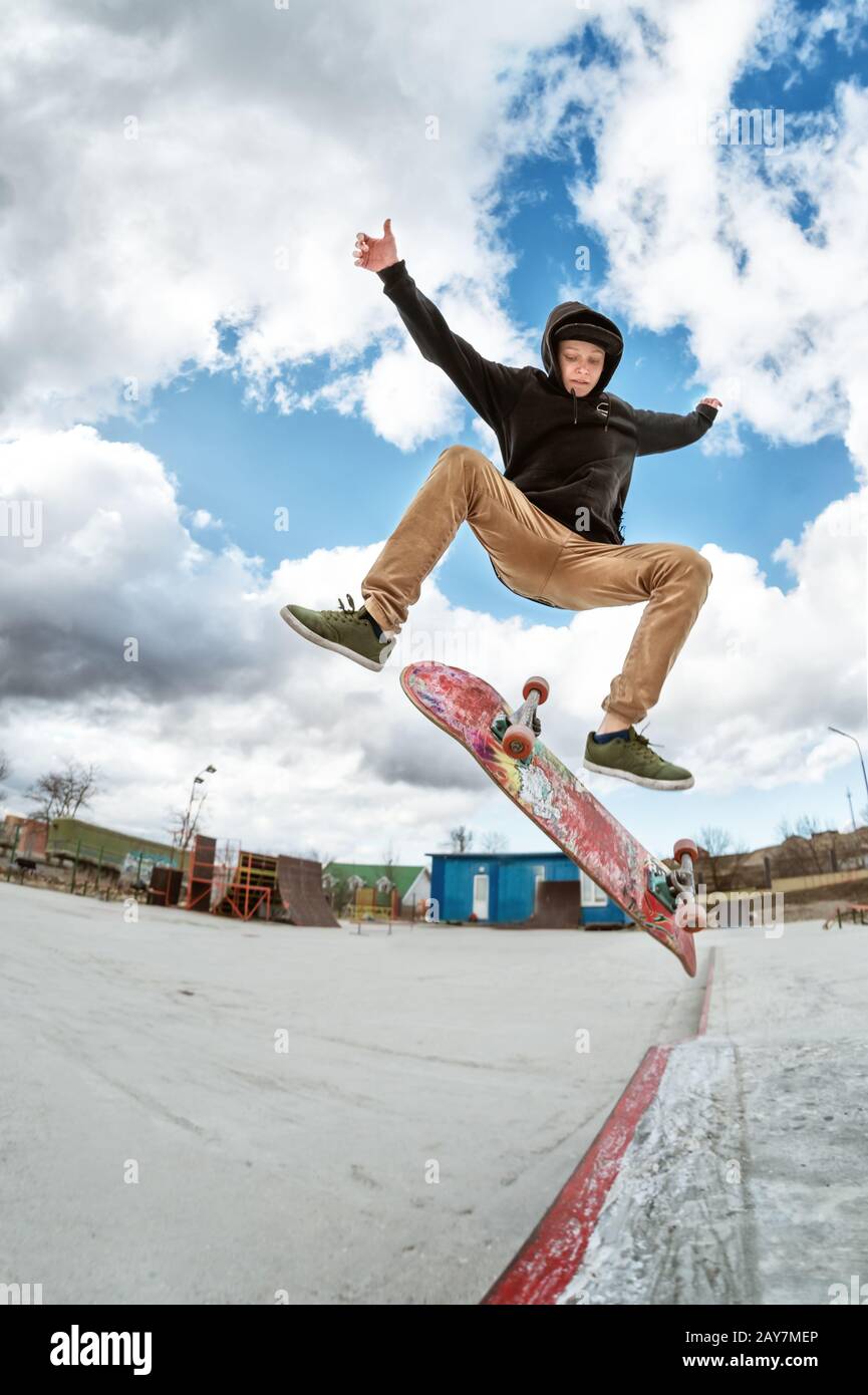 A young skateboarder makes Wallie in a skatepark, jumping on a skateboard into the air with a coup Stock Photo