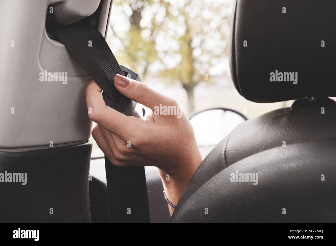 A woman's hand reaches behind her seat belt to fasten it. Stock Photo