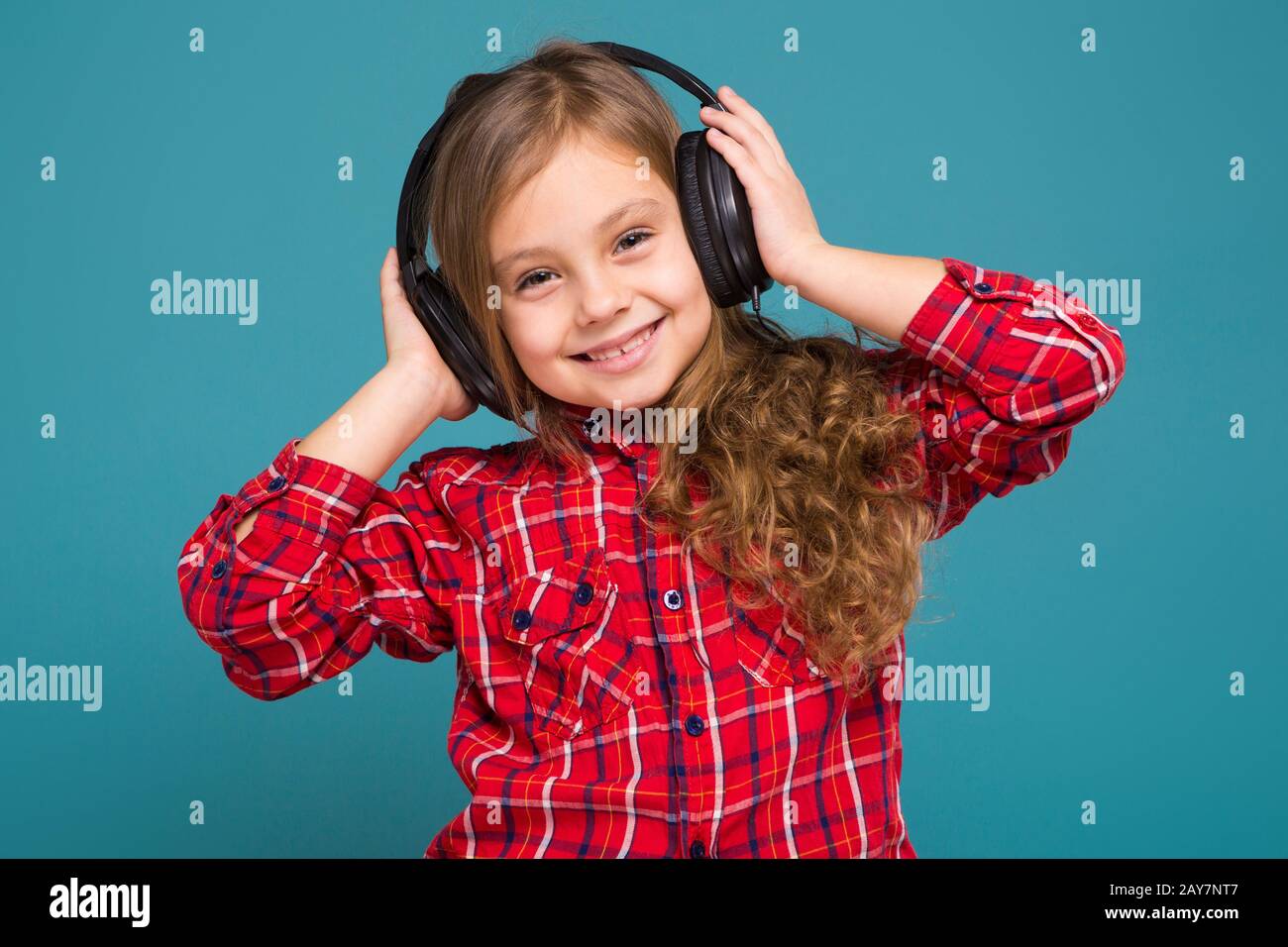 Pretty, little girl in checkered shirt and earphones with brown hair Stock Photo