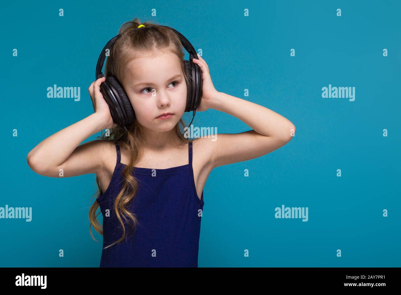 Pretty, little girl in shirt and earphones with brunet hair Stock Photo