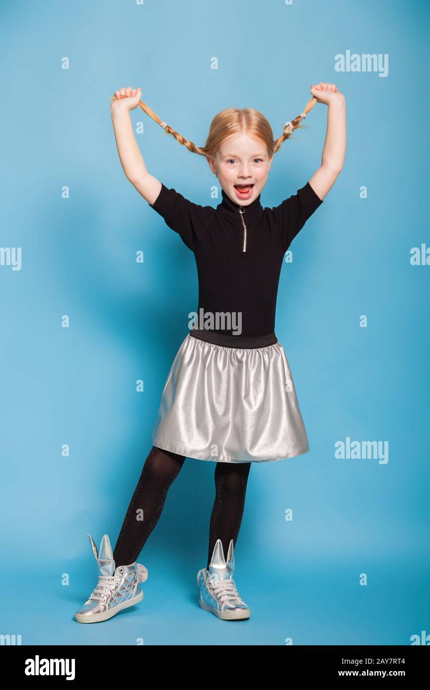 little girl with braids in stylish clothes on blue background Stock Photo