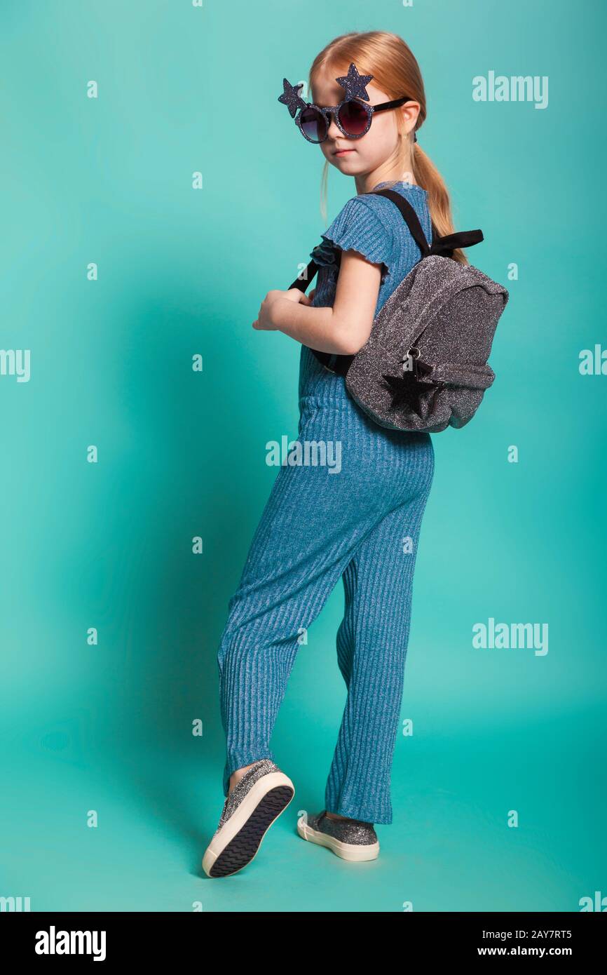 little girl with a tail in stylish clothes and sunglasses on blue