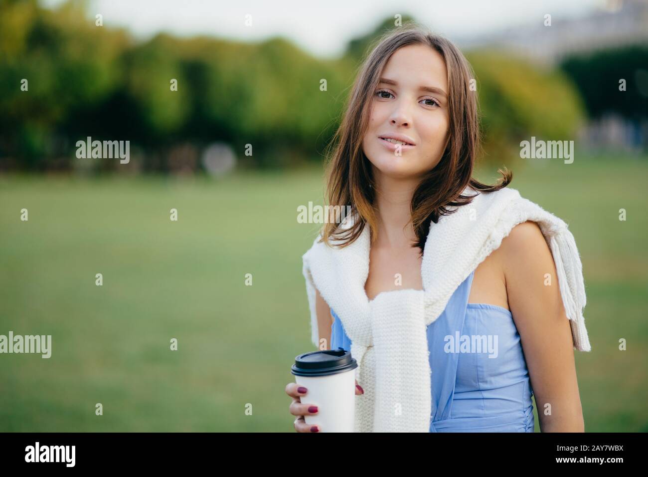 People, recreation and lifestyle concept. Beautiful young European woman has serious look at camera, dressed casually, spends free time at nature, dri Stock Photo