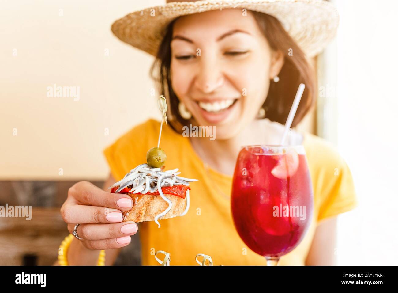 Young woman enjoying tasty traditional spanish snack tapas, with glass