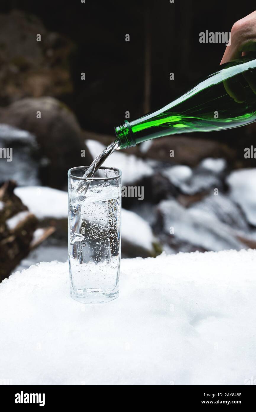 Mineral mineral water is poured from a glass green bottle into a clear