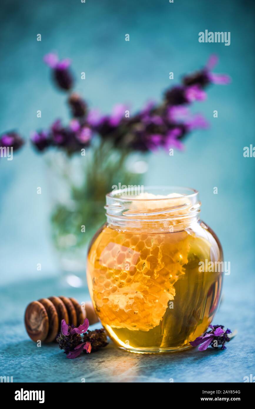 Jar with honey and comb on vibrant background Stock Photo