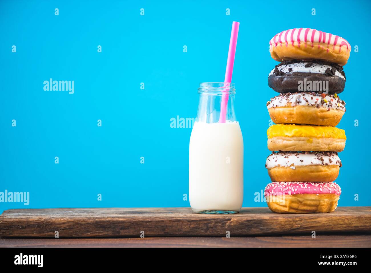 Milk bottle and stack of donuts on wooden board Stock Photo