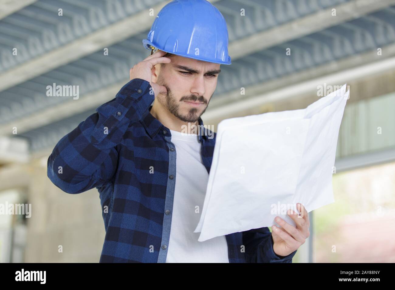 thoughtful young worker with plans indoors Stock Photo