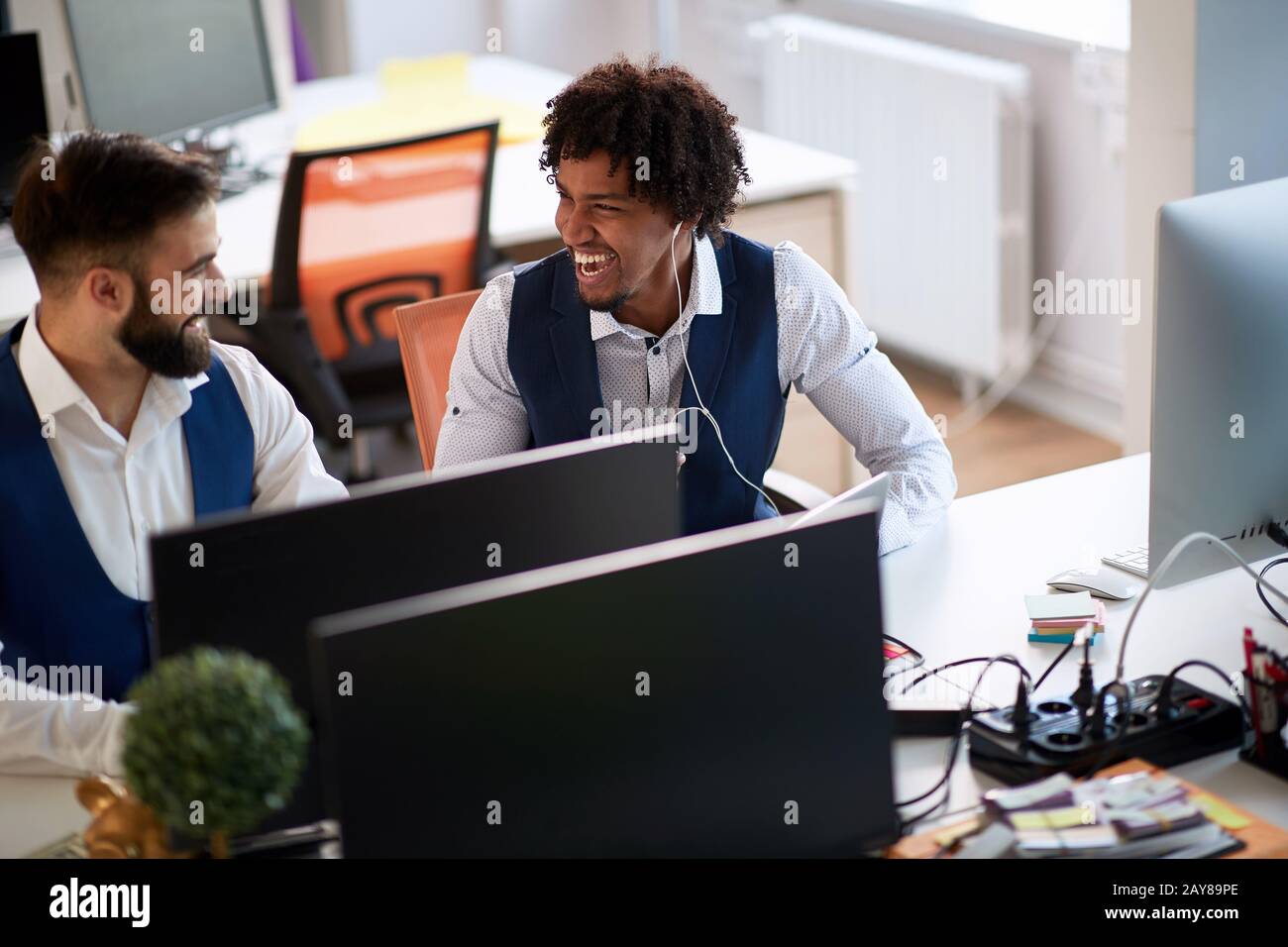 two colleagues talking and laughing in modern office. funky business concept Stock Photo