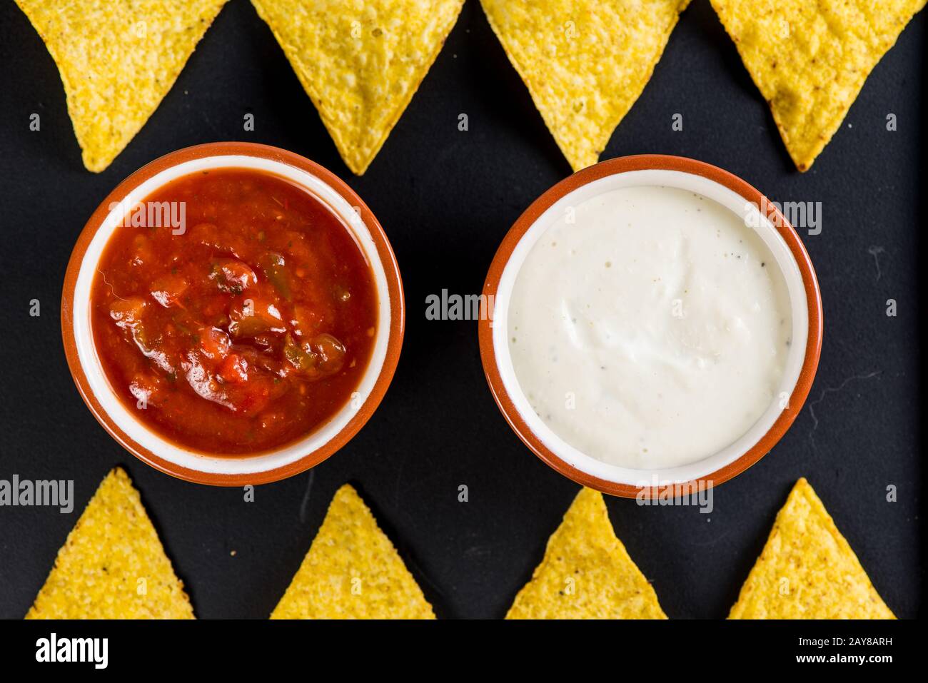 mexican street food nachos  with salsa and cream dip on black background Stock Photo