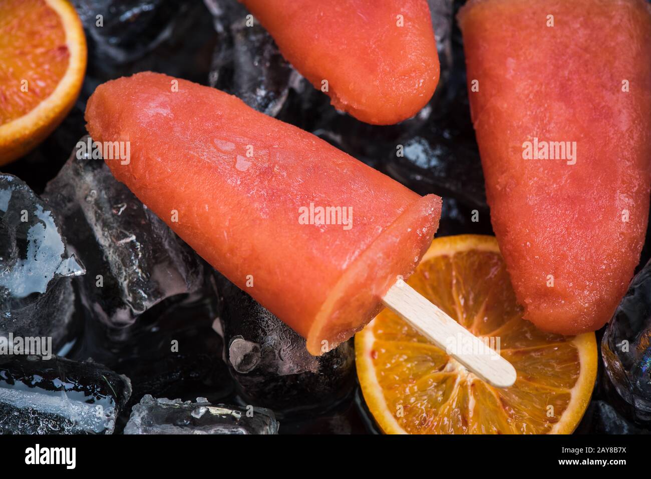 Orange juice popsicles over ice Stock Photo