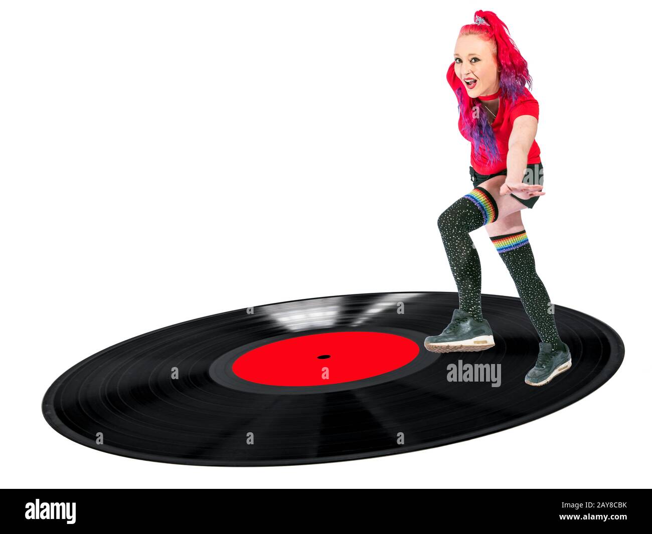 Woman with red hair and knee socks dancing on a vinyl record laughing Stock Photo