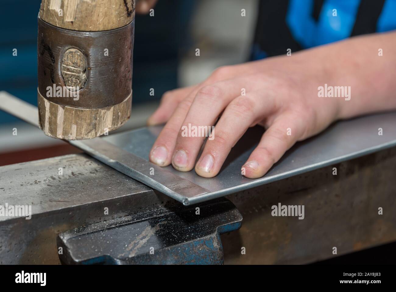 Craftsman folds sheet edges with a mallet - close-up Stock Photo