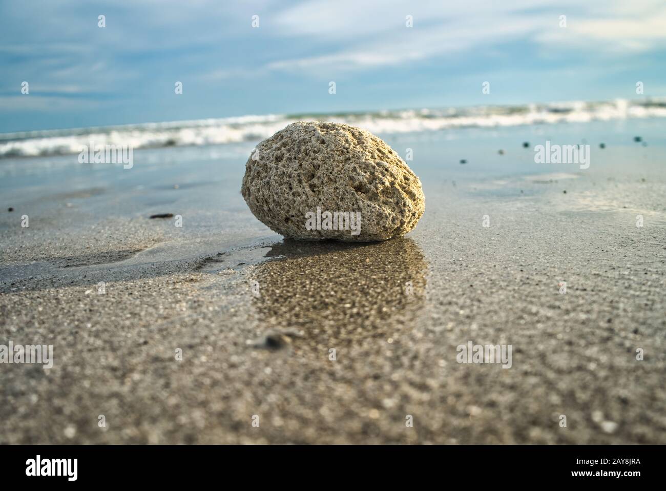 Focus on a stone at the beach with horizon and ocean in background Stock Photo