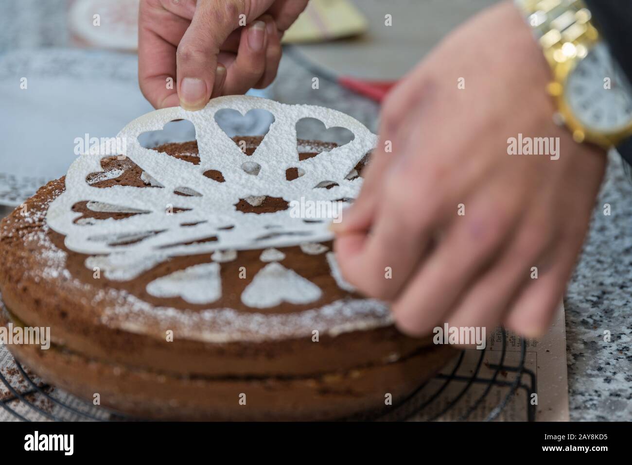 confectioner designs dark cake with stencil - close-up Stock Photo