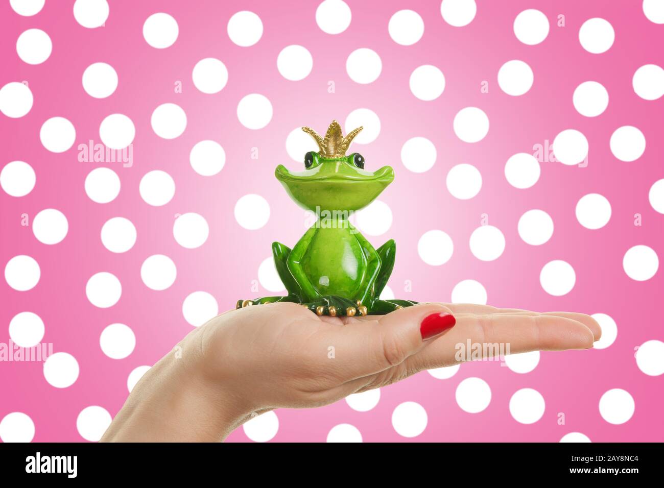 Female hand is holding frog prince, concept for dating, love and valentines day Stock Photo