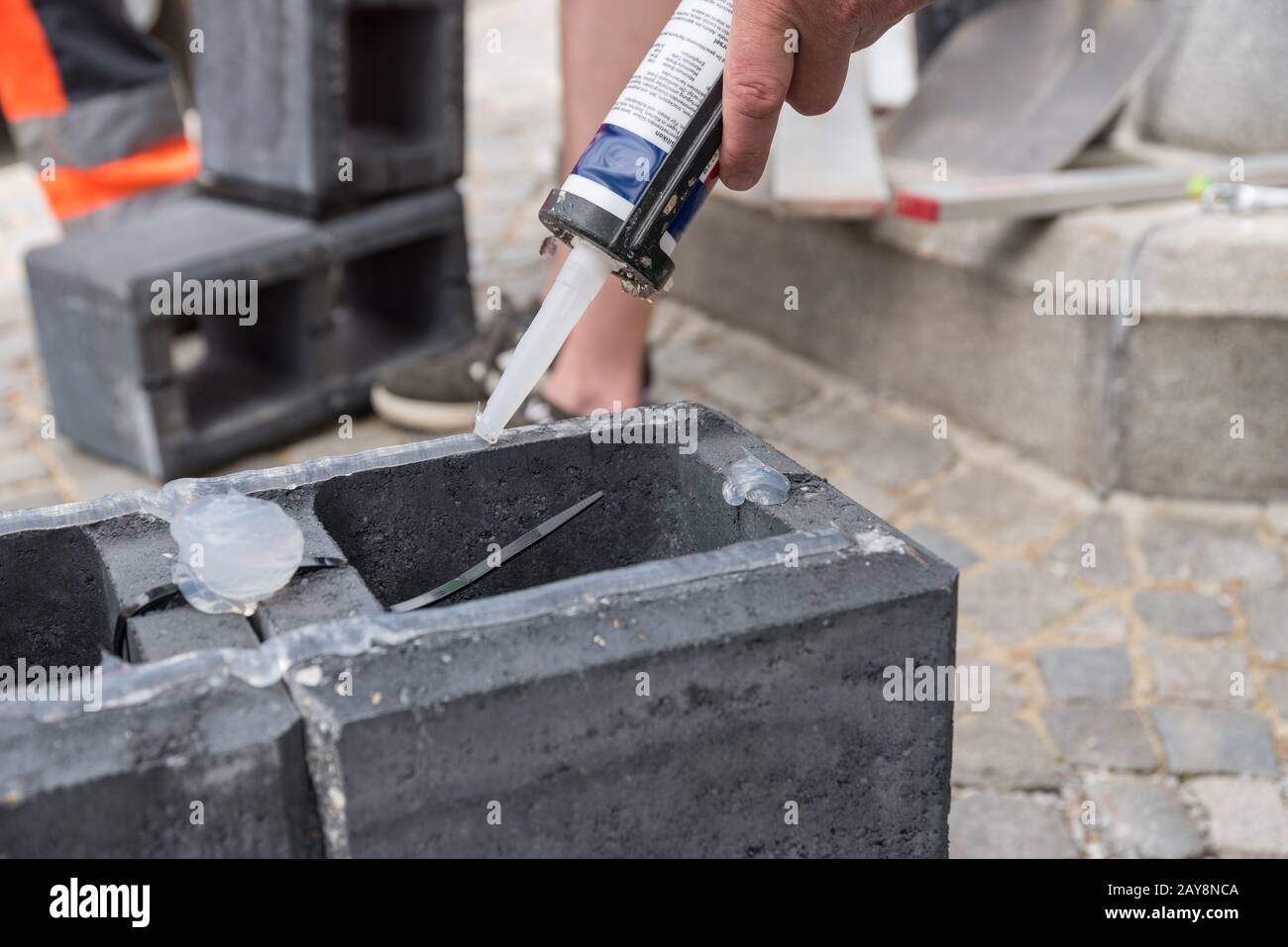 Bricklayer on a building site with concrete bricks and silicone - close-up Stock Photo